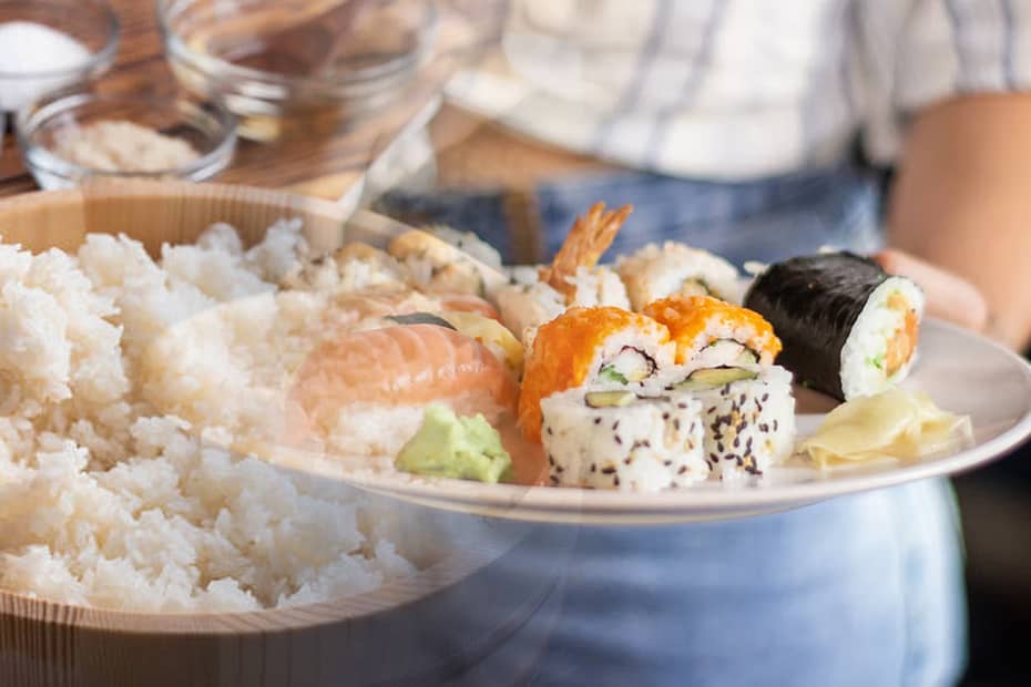 Sushi preparation, rice in a wooden bucket, sushi dishes on a plate.