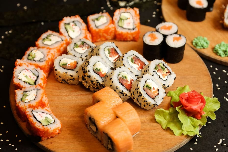 An assortment of sushi, with ginger, wasabi and sesame seeds on a wooden table